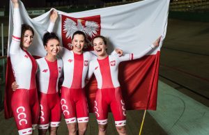 dziewczyny z torowej reprezentacji Polski w nowych strojach F4, na tle flagi narodowej