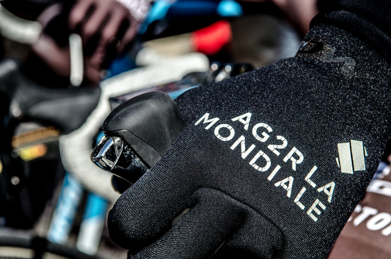 Dłoń na kierownicy w rękawiczce grupy Ag2r la Mondiale