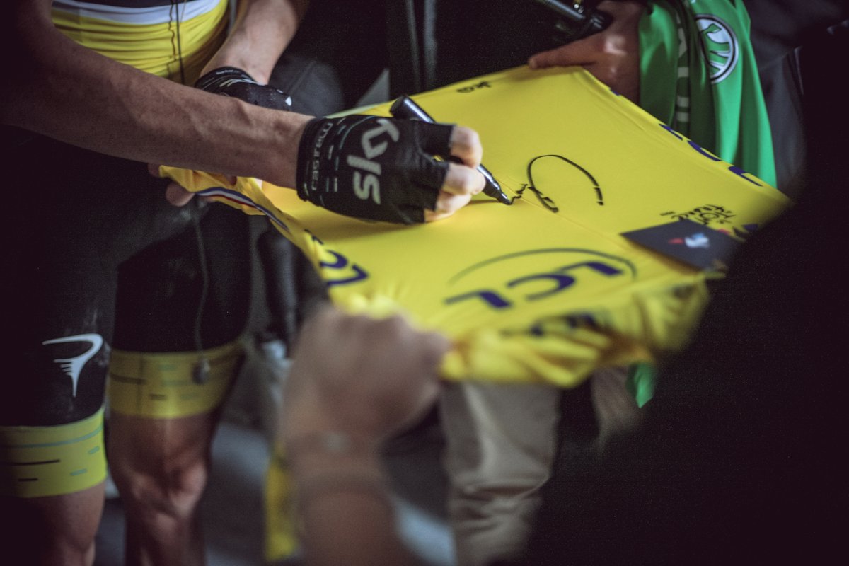 Chris Froome skłda podpis na żółtej koszulce TdF