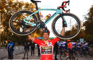 Primoz Roglic w czerwonej koszulce lidera Vuelta a Espana unosi w górę rower Bianchi, na którym wygrał Vuelta a Espana 2020.