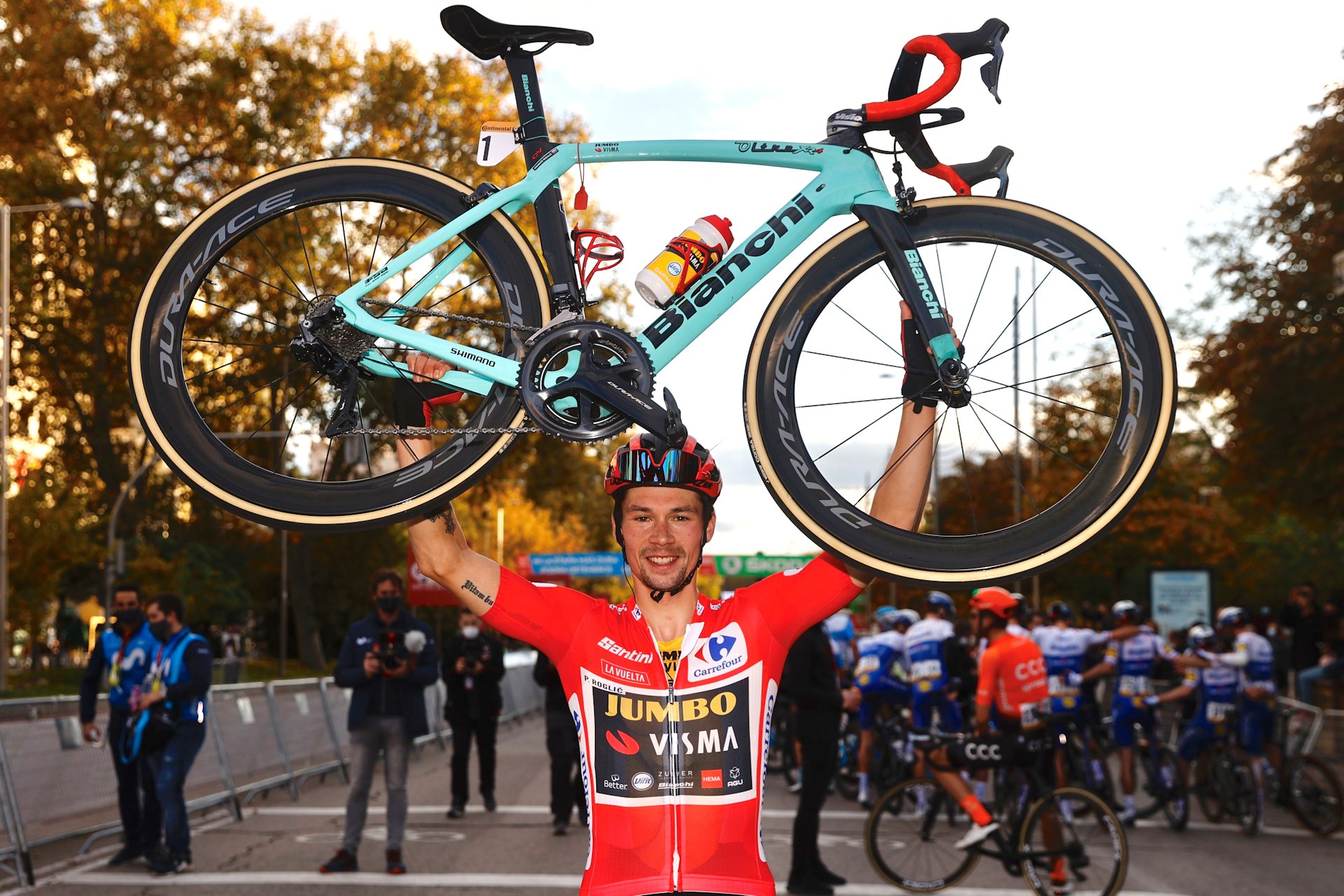 Primoz Roglic w czerwonej koszulce lidera Vuelta a Espana unosi w górę rower Bianchi, na którym wygrał Vuelta a Espana 2020.