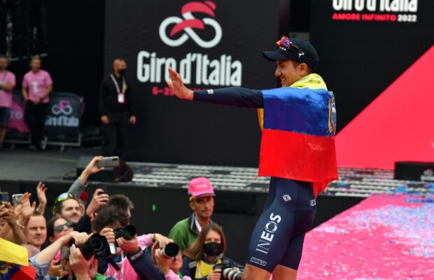 Richard Carapaz na scenie Giro d'Italia owinięty we flagę Ekwadoru