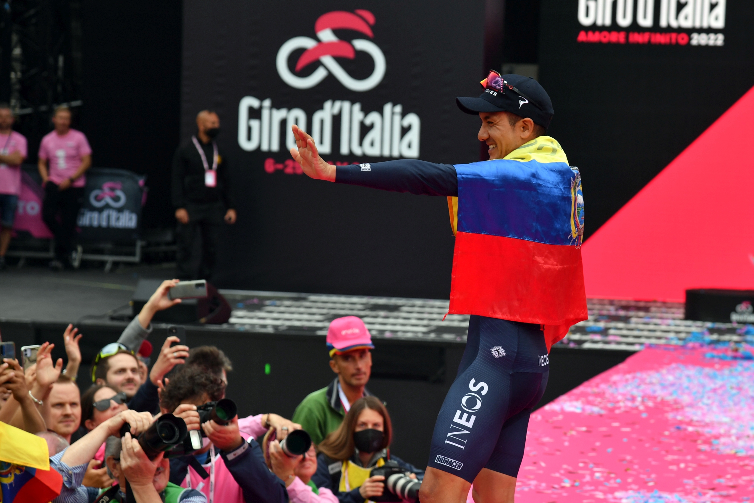 Richard Carapaz na scenie Giro d'Italia owinięty we flagę Ekwadoru