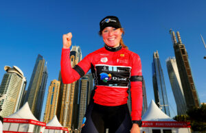 Charlotte Kool w czerwonej koszulce liderki UAE Tour na tle drapaczy Dubaju